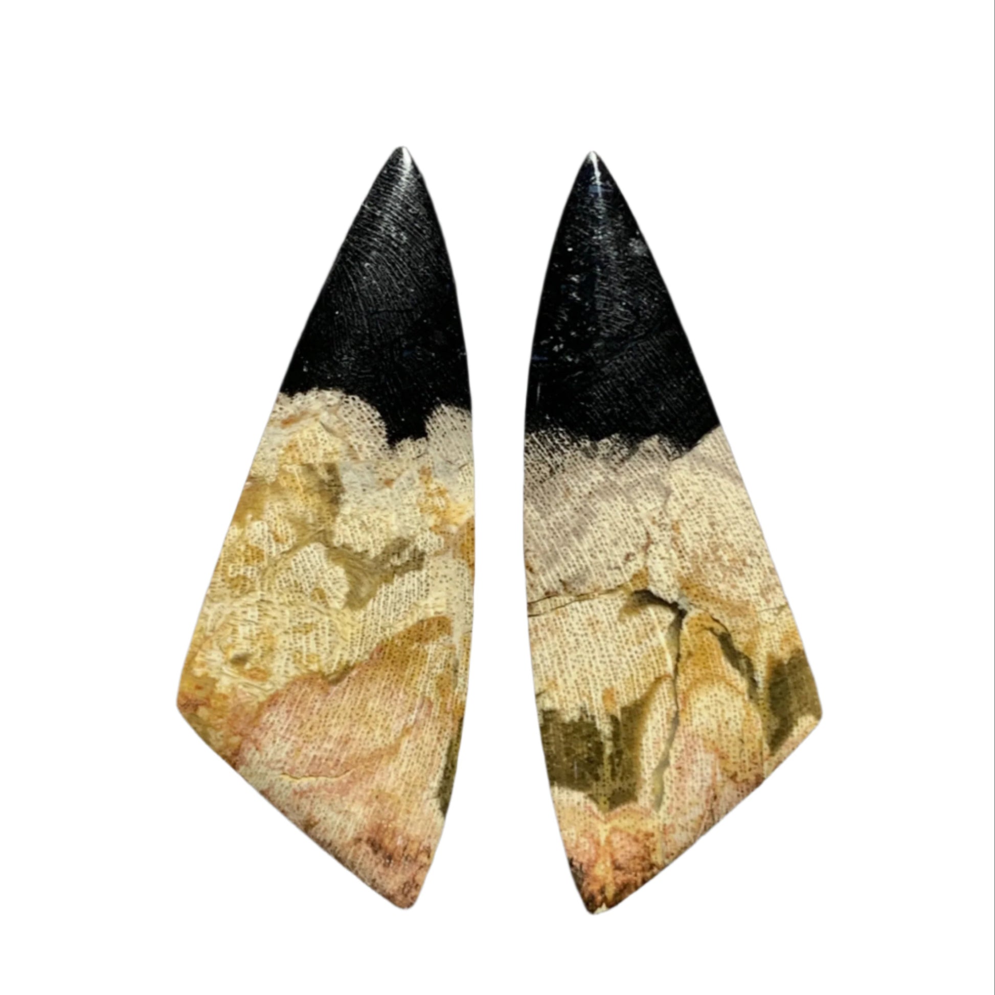 Pair of unique earrings with black and beige design held between fingers against a dark background